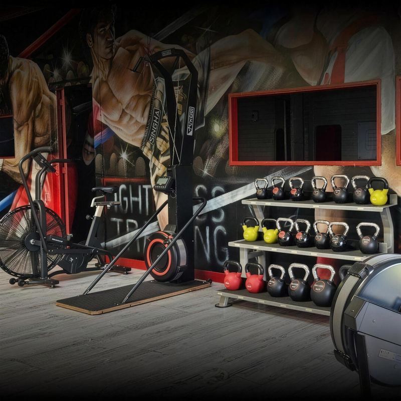 Le logo Fightness Training peint au mur, au-dessus des kettlebells