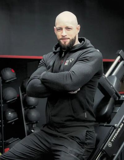 Kevin, co-gérant et coach sportif, bras croisés dans la salle