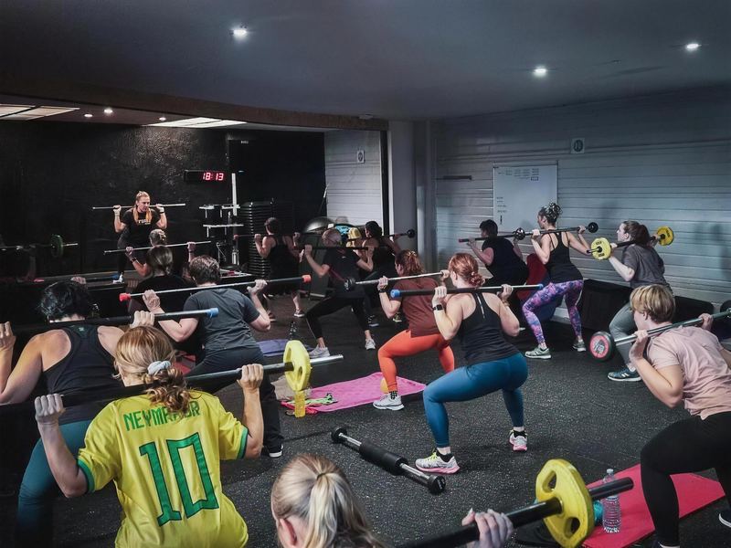 Un cours de Pump dans la salle de cours collectifs, barres sur les épaules