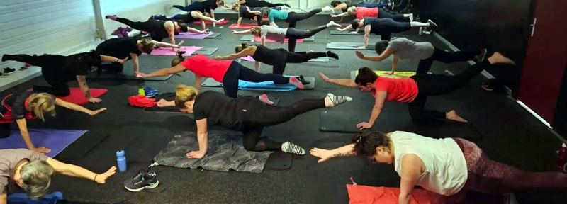 Un cours collectif, les adhérentes en exercice au sol sur leurs tapis